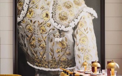 Restaurant interior with bar seating, gold upholstered chairs, marble tables, and large statement artwork at M Social New York Downtown.