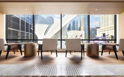 Seating area with large windows overlooking city architecture and natural light-filled space at M Social New York Downtown.