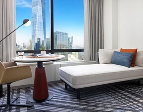 Seating area with chaise lounge, table, and floor-to-ceiling window showcasing city views at M Social New York Downtown.