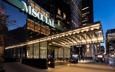 Hotel exterior entrance with illuminated canopy, glass façade, and city street view at M Social New York Downtown.