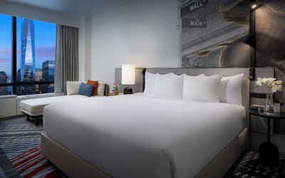King room with plush bed, city skyline view, seating area, and modern décor at M Social New York Downtown.