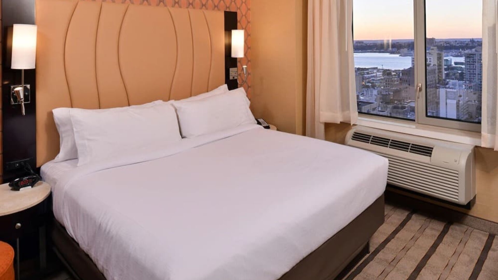 Guest room with king bed and large window allowing natural light and city views at Holiday Inn New York City - Times Square By IHG.