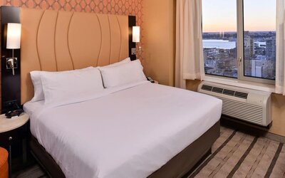 Guest room with king bed and large window allowing natural light and city views at Holiday Inn New York City - Times Square By IHG.