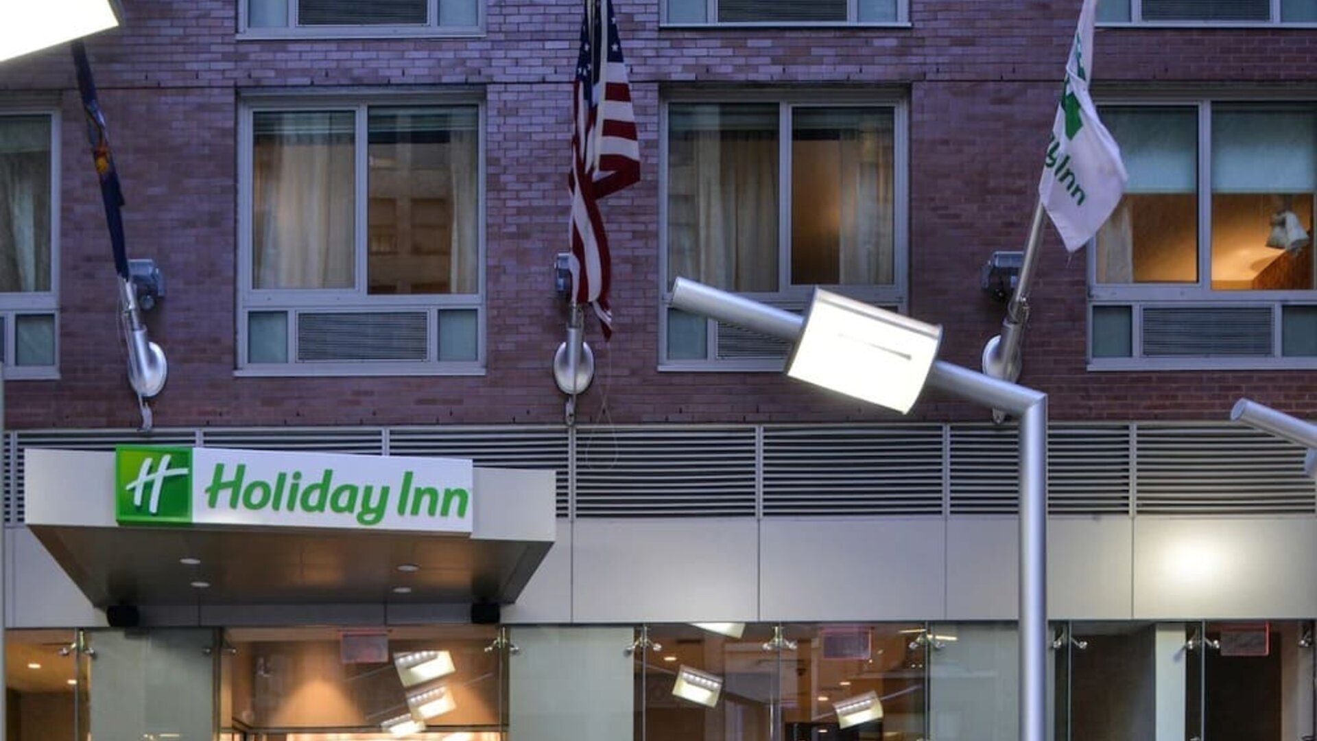 Exterior view of the hotel building façade with signage and flags at Holiday Inn New York City - Times Square By IHG.