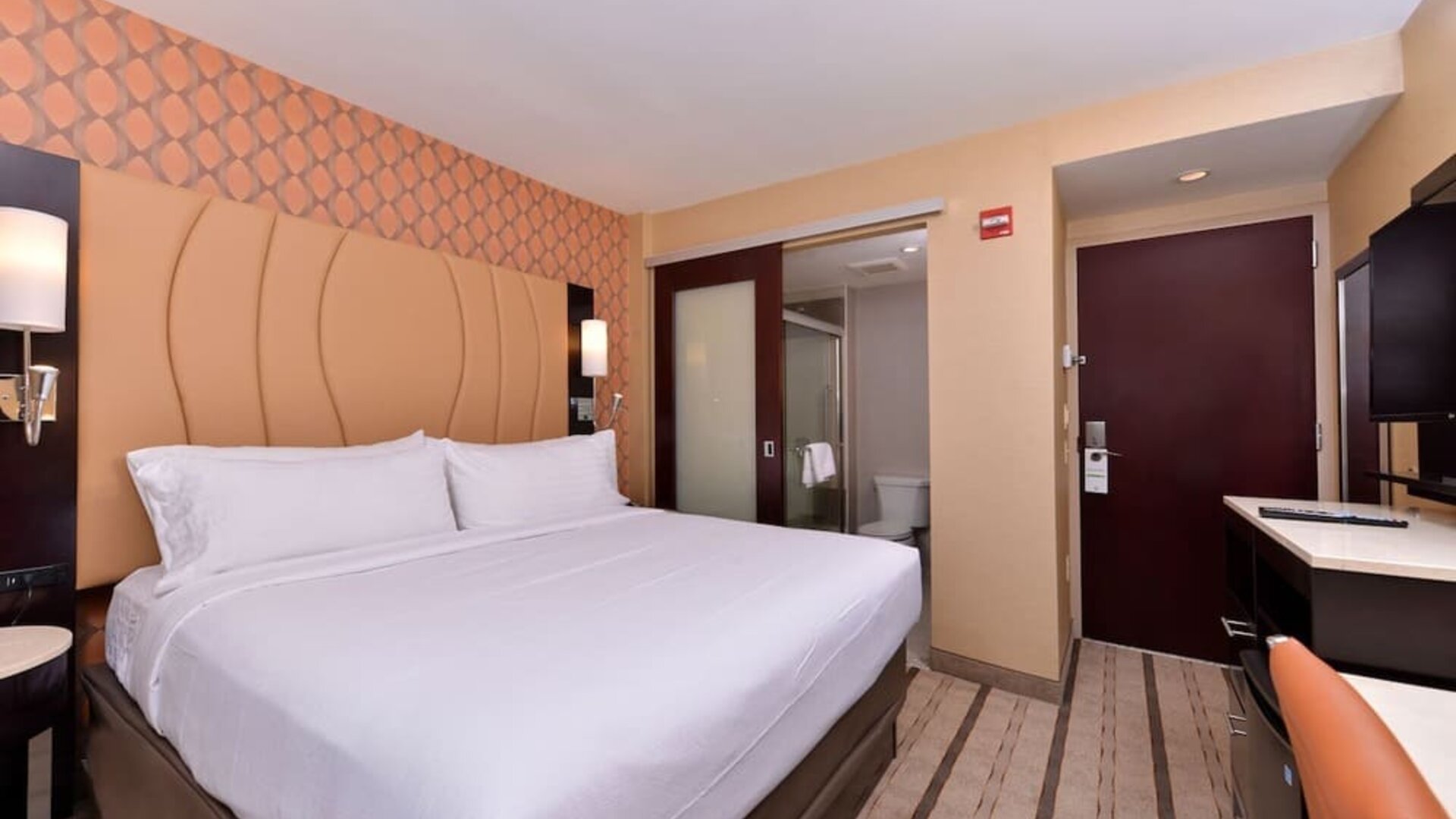 Guest room with king bed, modern décor, and bathroom entrance at Holiday Inn New York City - Times Square By IHG.