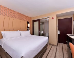 Guest room with king bed, modern décor, and bathroom entrance at Holiday Inn New York City - Times Square By IHG.