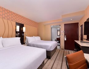 Guest room with two double beds, modern furnishings, and workspace area at Holiday Inn New York City - Times Square By IHG.