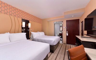Guest room with two double beds, modern furnishings, and workspace area at Holiday Inn New York City - Times Square By IHG.