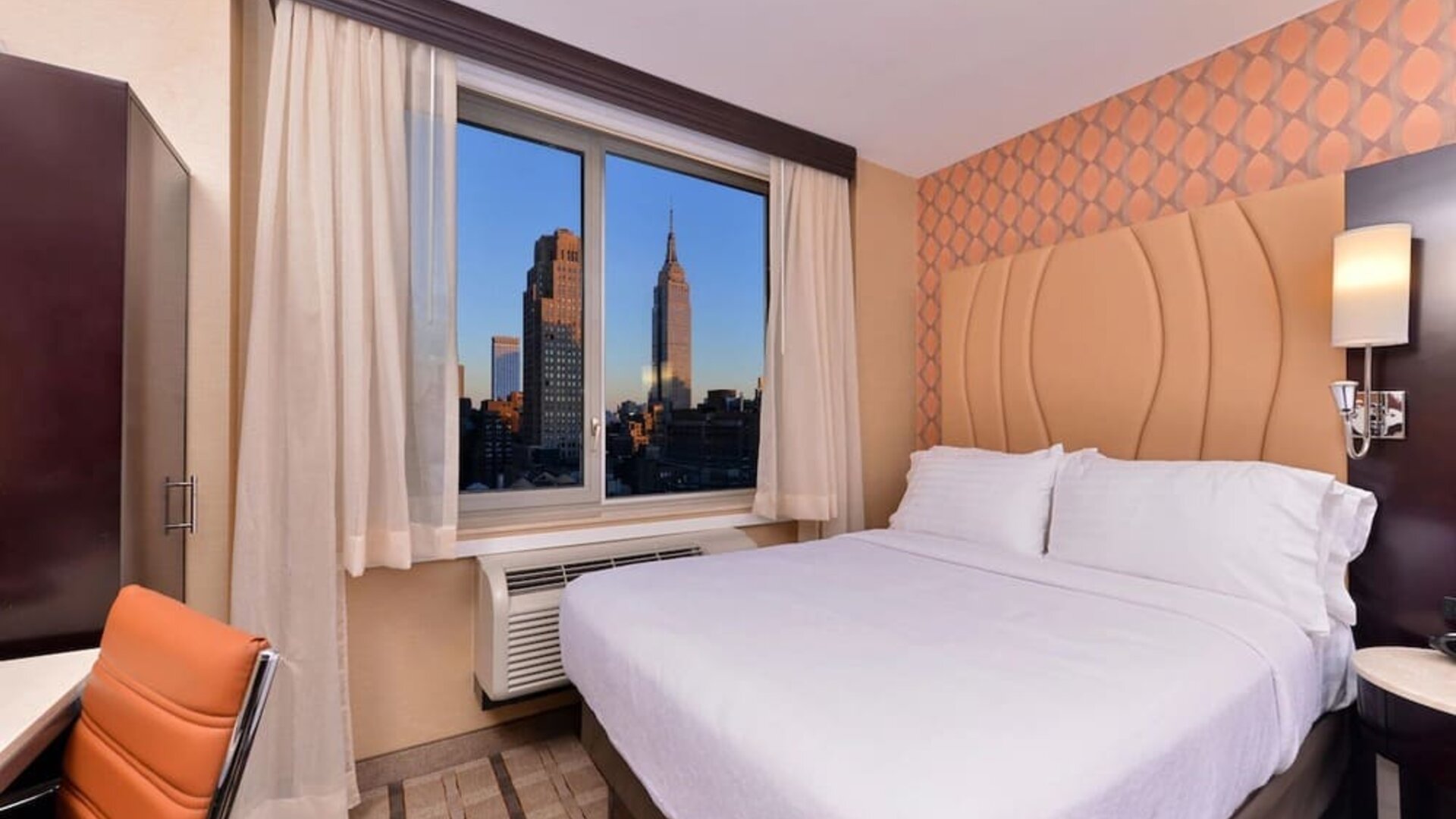 Guest room with king bed and large window showcasing city skyline views at Holiday Inn New York City - Times Square By IHG.
