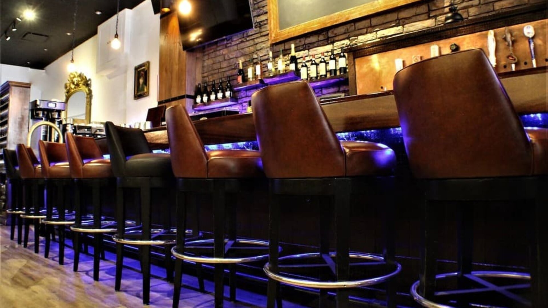 Bar area with high stools, wooden finishes, and illuminated shelving at Holiday Inn New York City - Times Square By IHG.