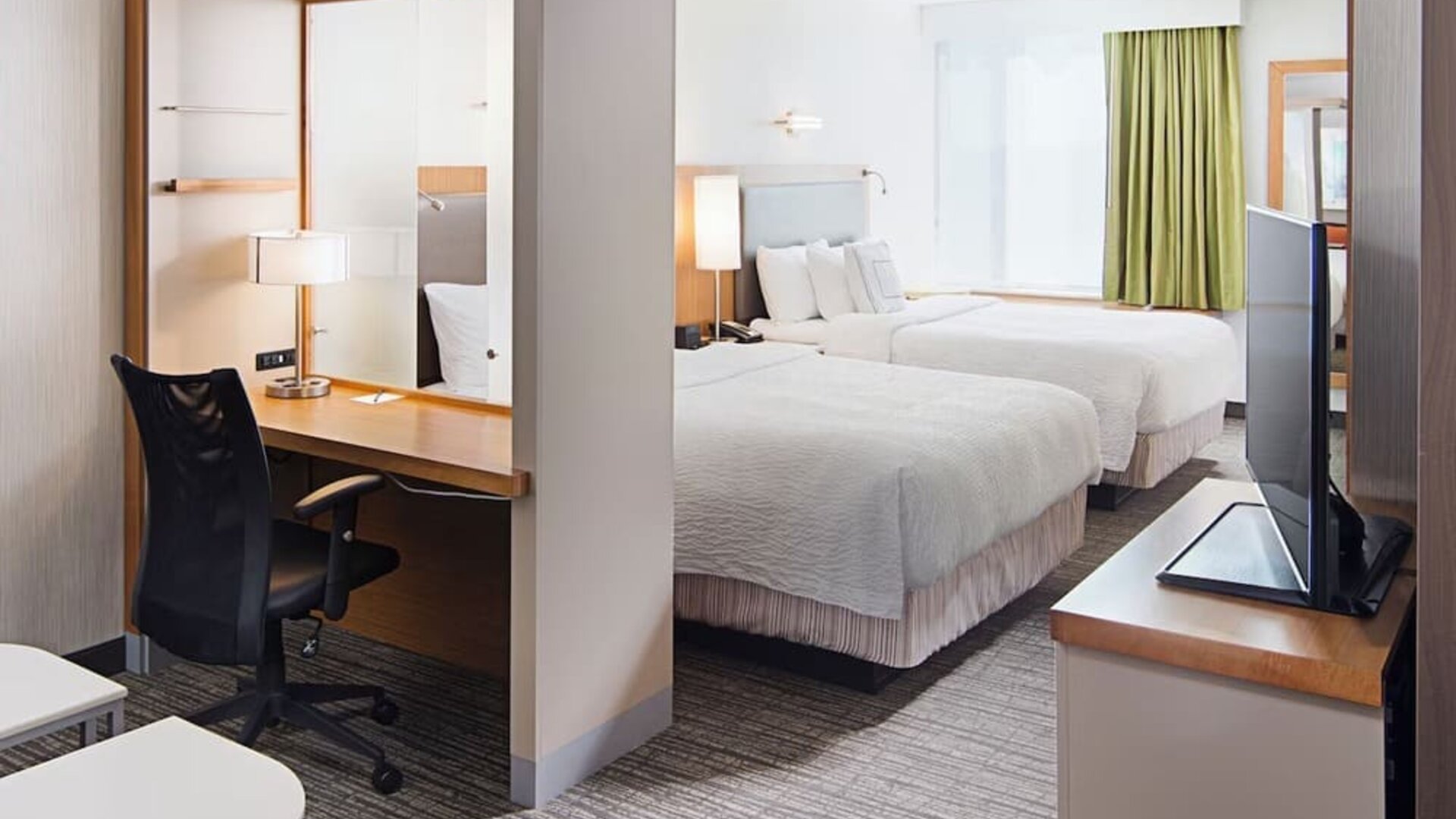 Guest room with two double beds, workspace desk, chair, and television area at Springhill Suites Carle Place.