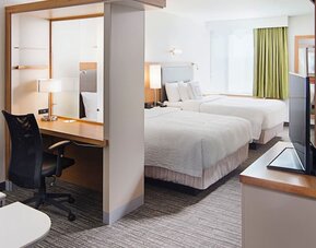 Guest room with two double beds, workspace desk, chair, and television area at Springhill Suites Carle Place.