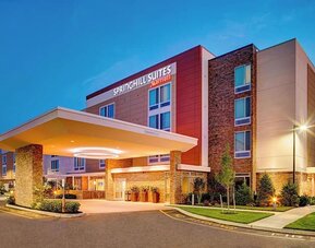 Exterior view of the hotel building with covered entrance and landscaping at Springhill Suites Carle Place.