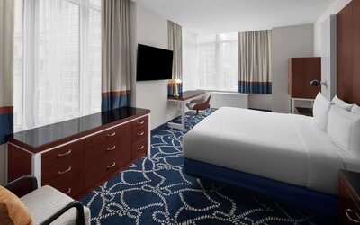 Guest room with king bed, workspace desk, chair, and large windows at Hilton Brooklyn New York.