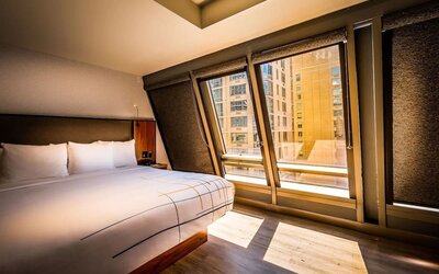 Guest room with king bed and large angled windows providing natural light and city views at La Quinta Times Square South.