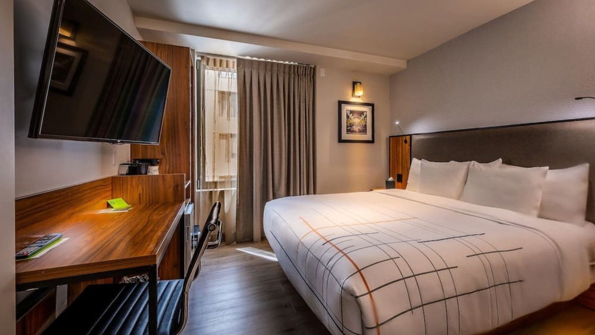 Guest room with king bed, workspace desk, chair, and wall-mounted TV at La Quinta Times Square South.