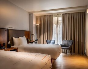 Guest room with two double beds, seating area, and large window with natural light at La Quinta Times Square South.