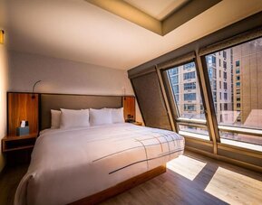 Guest room with king bed and angled floor-to-ceiling windows offering city views at La Quinta Times Square South.