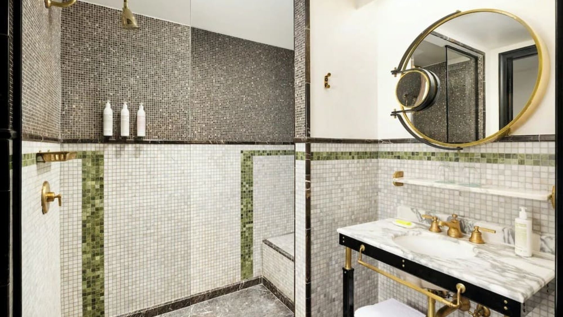 Bathroom with walk-in shower, mosaic tile walls, marble sink, and gold fixtures at Le Méridien New York, Central Park.