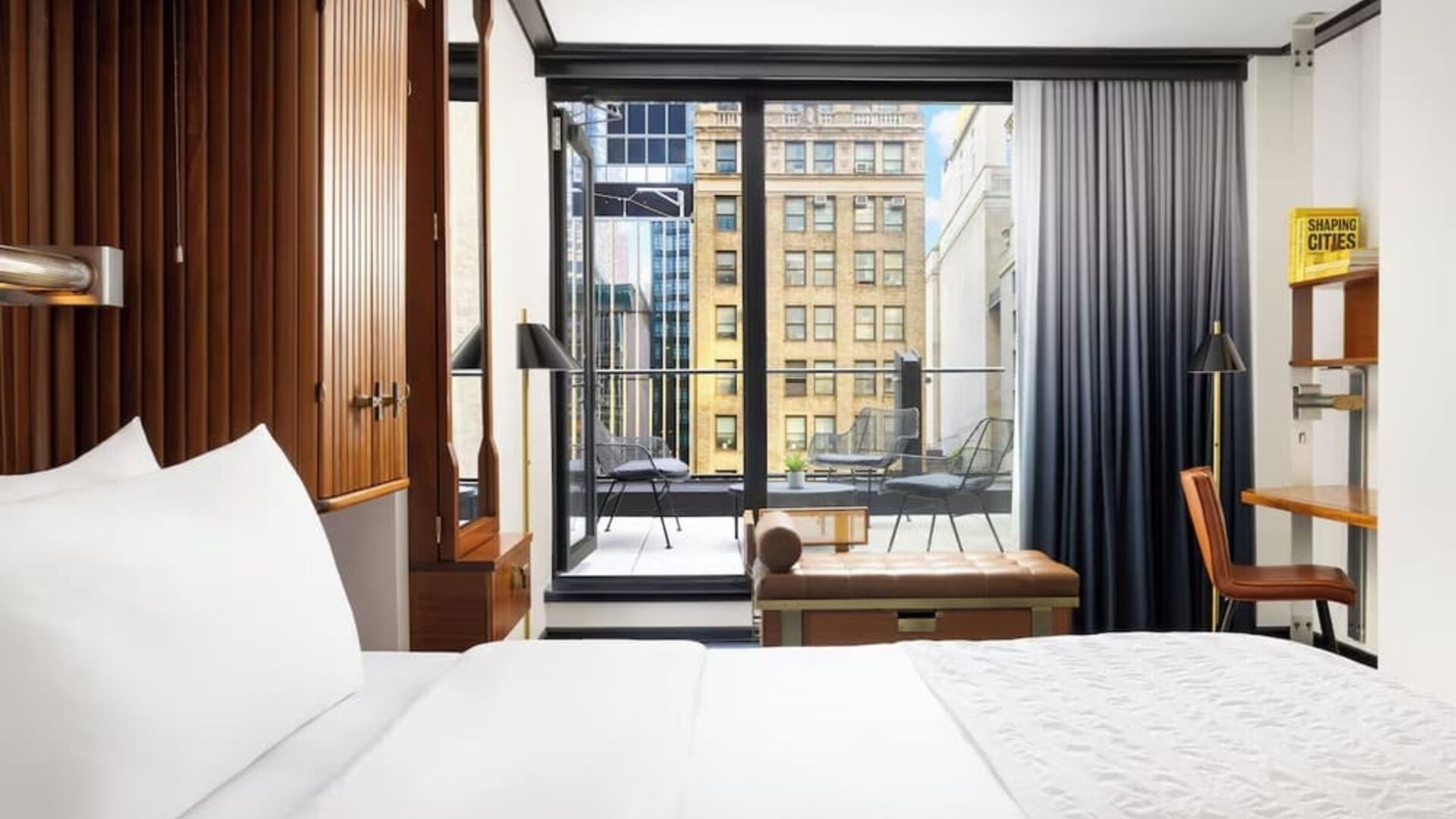 Guest room with king bed, workspace, and balcony access with city views at Le Méridien New York, Central Park.