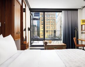 Guest room with king bed, workspace, and balcony access with city views at Le Méridien New York, Central Park.