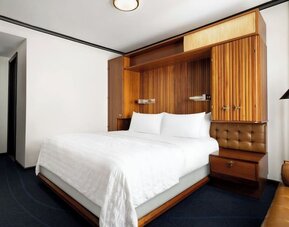 Guest room with king bed, modern décor, and workspace area at Le Méridien New York, Central Park.