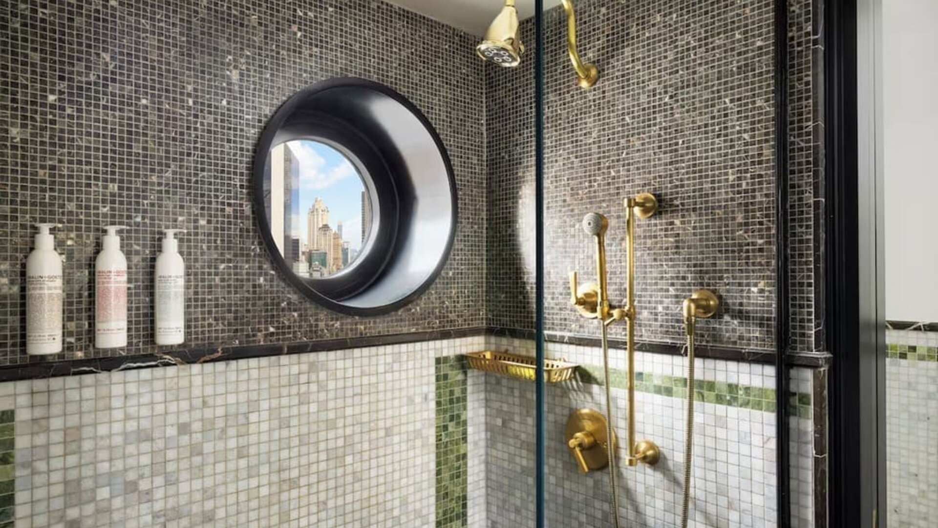 Bathroom with walk-in shower, mosaic tiles, and gold fixtures at Le Méridien New York, Central Park.