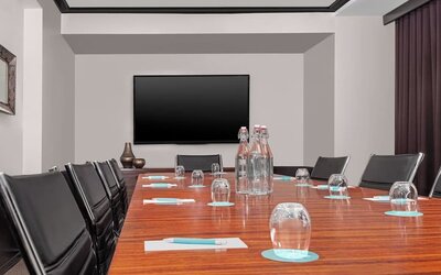 Meeting room with conference table, chairs, and presentation screen at Le Méridien New York, Central Park.