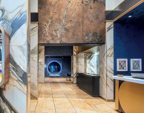 Lobby area with marble finishes, artwork, and reception desk at Le Méridien New York, Central Park.