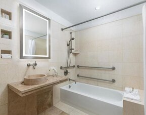 Accessible bathroom with bathtub, grab rails, and stone finishes at Hotel 57.