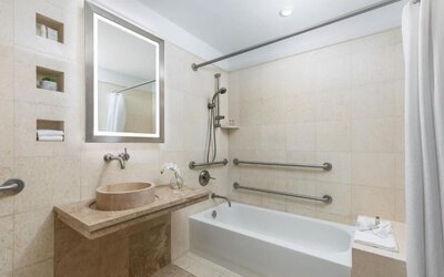 Accessible bathroom with bathtub, grab rails, and stone finishes at Hotel 57.