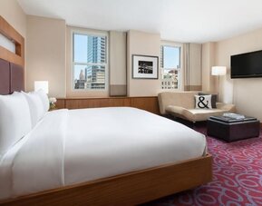 Guest room with king bed, sofa seating, and city views at Hotel 57.