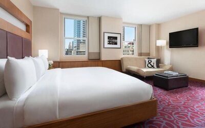 Guest room with king bed, sofa seating, and city views at Hotel 57.