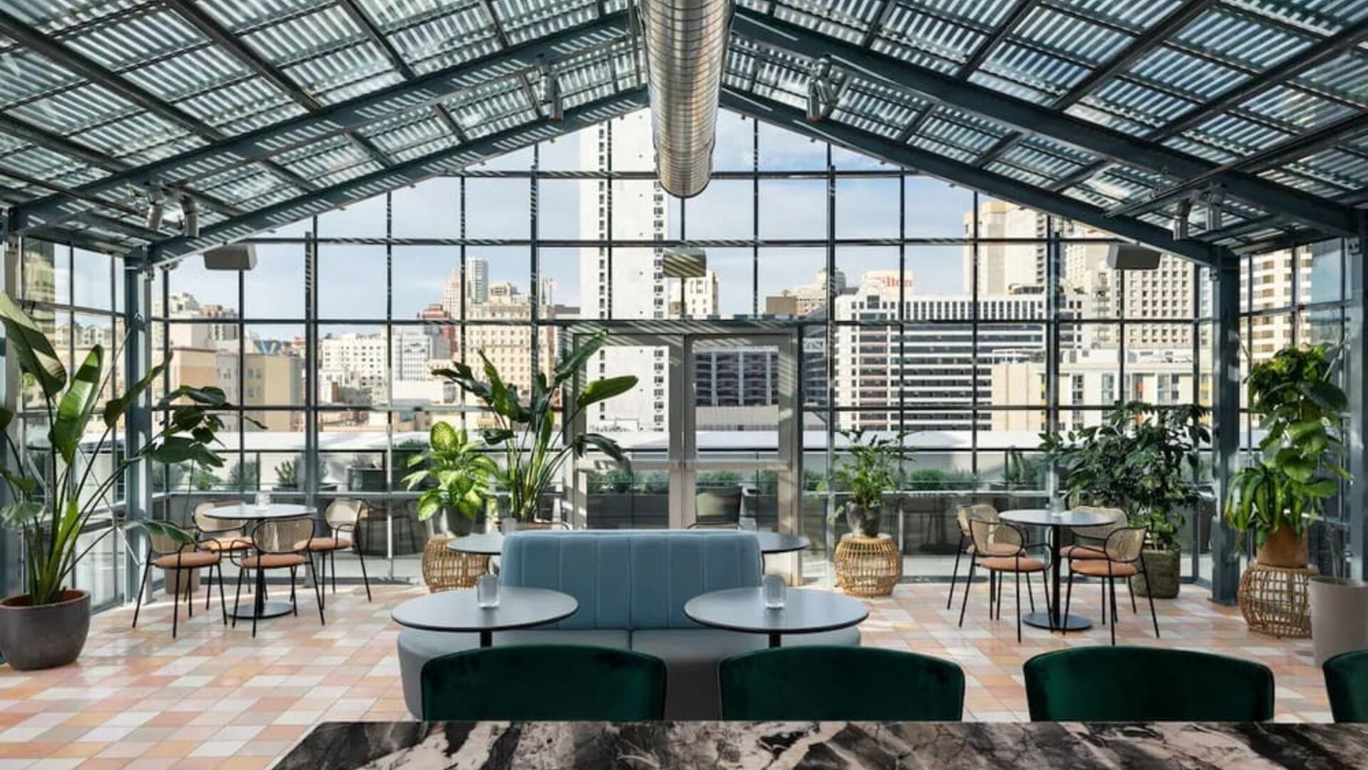 Bright indoor dining space with large glass ceiling, greenery, and city views at Timbri Hotel San Francisco, Curio Collection By Hilton