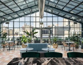 Bright indoor dining space with large glass ceiling, greenery, and city views at Timbri Hotel San Francisco, Curio Collection By Hilton
