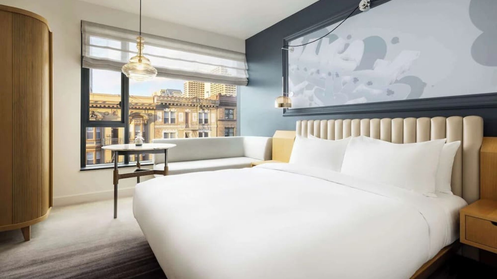 Modern bedroom with large bed, accent wall, and city view seating area at Timbri Hotel San Francisco, Curio Collection By Hilton.