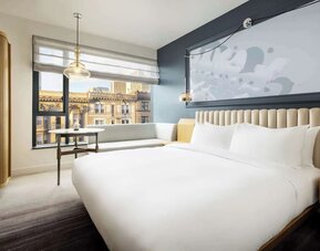 Modern bedroom with large bed, accent wall, and city view seating area at Timbri Hotel San Francisco, Curio Collection By Hilton.