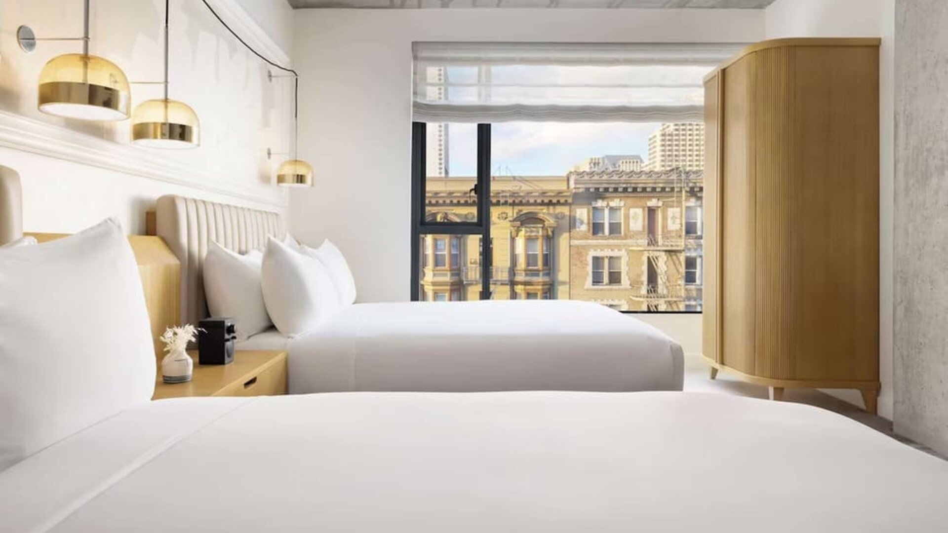 Stylish twin room with two beds, warm lighting, and city-facing window at Timbri Hotel San Francisco, Curio Collection By Hilton.