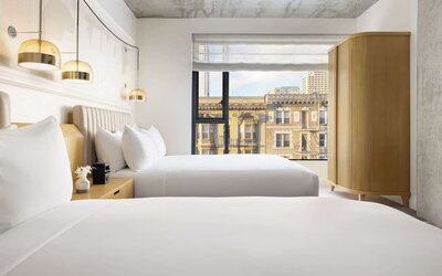 Stylish twin room with two beds, warm lighting, and city-facing window at Timbri Hotel San Francisco, Curio Collection By Hilton.