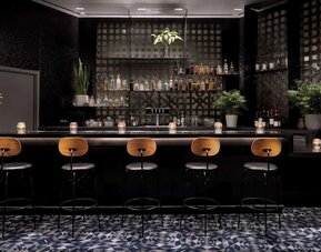 Elegant bar area with high stools, ambient lighting, and a curated selection of drinks at Timbri Hotel San Francisco, Curio Collection By Hilton.