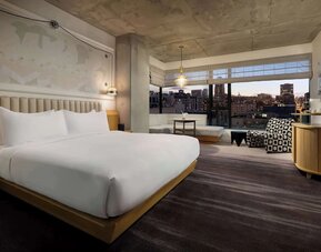 Comfortable king room with seating area, large windows, and warm interior tones at Timbri Hotel San Francisco, Curio Collection By Hilton.