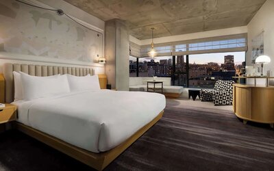 Comfortable king room with seating area, large windows, and warm interior tones at Timbri Hotel San Francisco, Curio Collection By Hilton.