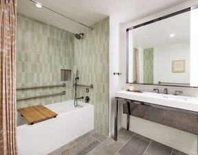Accessible bathroom with bathtub, grab rails, handheld shower, and modern vanity at Timbri Hotel San Francisco, Curio Collection By Hilton.