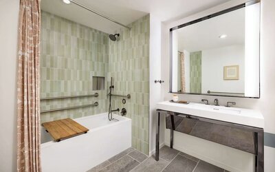 Accessible bathroom with bathtub, grab rails, handheld shower, and modern vanity at Timbri Hotel San Francisco, Curio Collection By Hilton.