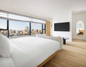 Bright modern room with large bed, floor-to-ceiling windows, and city views at Timbri Hotel San Francisco, Curio Collection By Hilton.