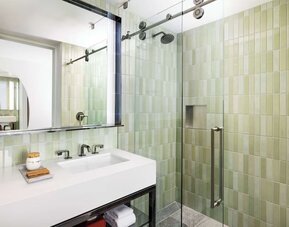 Modern bathroom with glass walk-in shower, green tile finish, and sleek vanity at Timbri Hotel San Francisco, Curio Collection By Hilton.