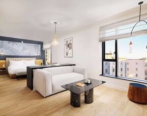 Bright suite with large bed, lounge seating, and expansive city views at Timbri Hotel San Francisco, Curio Collection By Hilton.