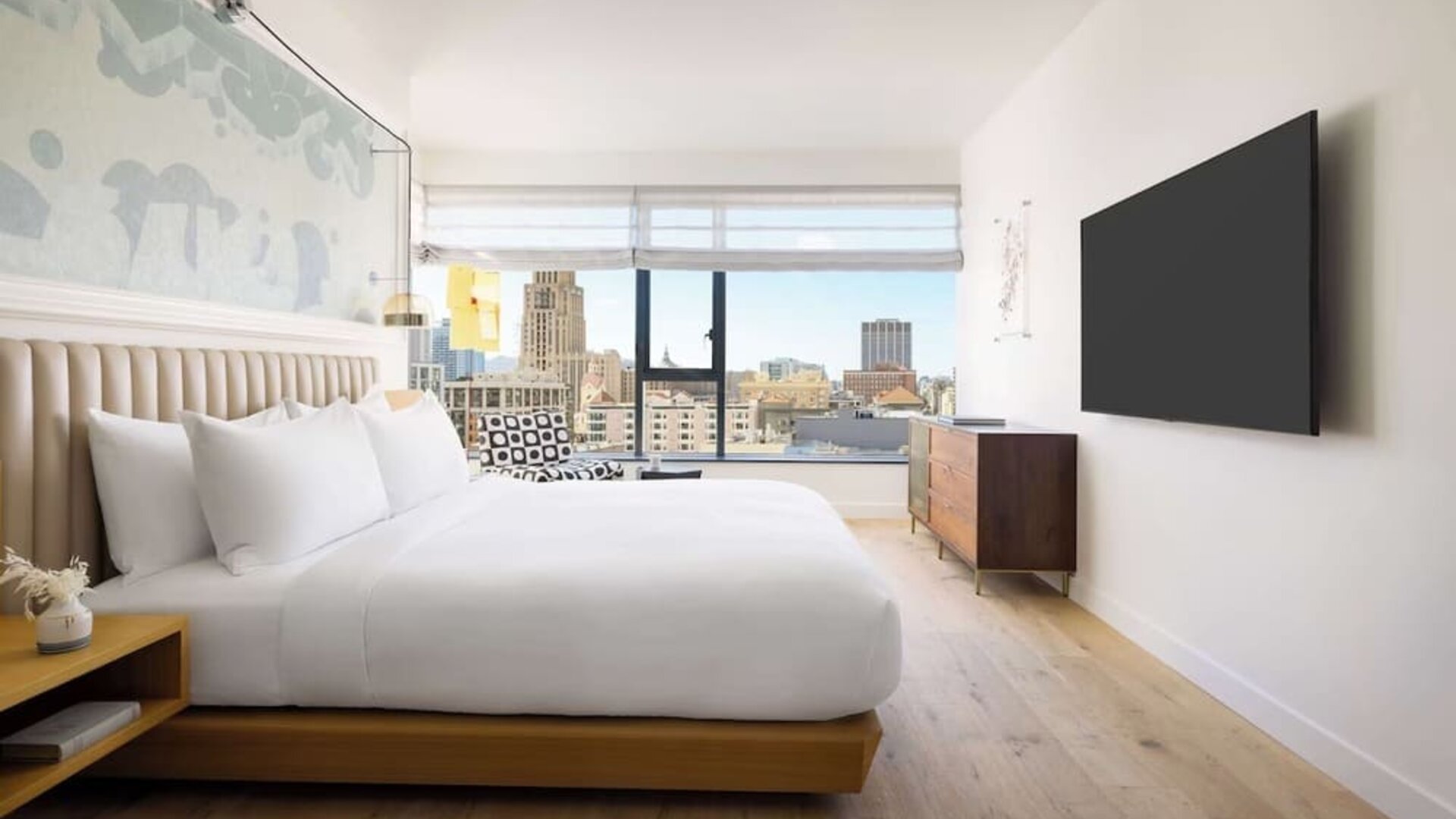 Modern king room with platform bed, wall-mounted TV, wooden furnishings, and large window offering city views at Timbri Hotel San Francisco, Curio Collection By Hilton.
