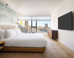 Modern king room with platform bed, wall-mounted TV, wooden furnishings, and large window offering city views at Timbri Hotel San Francisco, Curio Collection By Hilton.