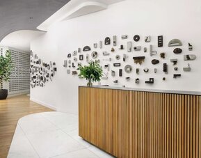 Reception area with wooden desk, artistic wall installation, and minimalist design at Timbri Hotel San Francisco, Curio Collection By Hilton.